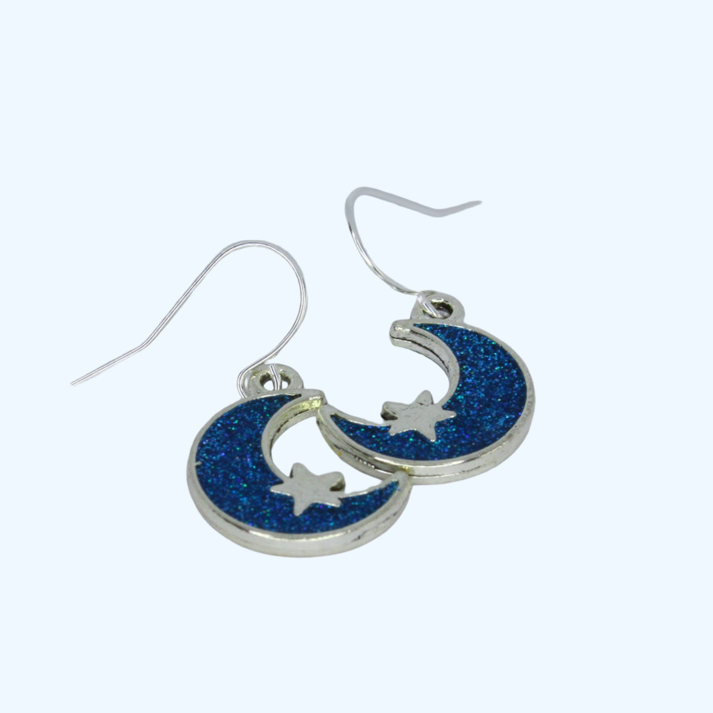 Moon and star earrings with blue glittery finish on a white background